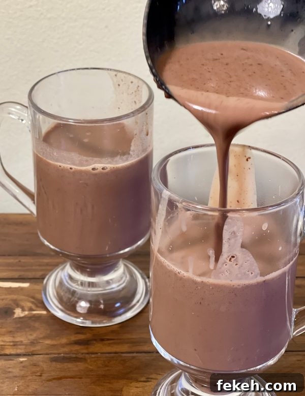 The Absolute Best Crockpot Hot Chocolate The Absolute Best Crockpot Hot Chocolate being poured into a clear mug