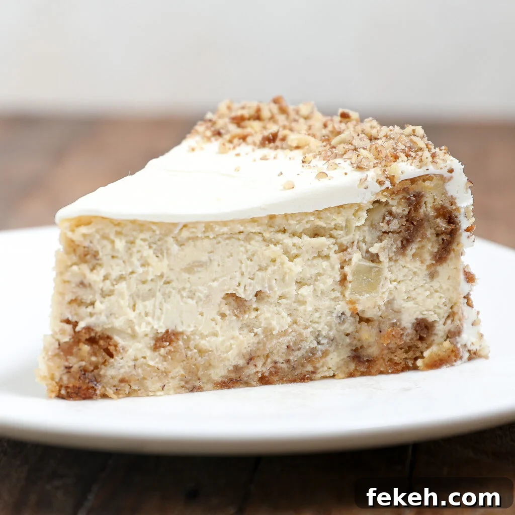44 Gluten-Free Dairy-Free Cake Recipes for Every Occasion 17 A slice of creamy Hummingbird Cake Cheesecake with a crumbly crust, topped with white frosting and sprinkled with chopped nuts, served on a white plate against a wooden table background.