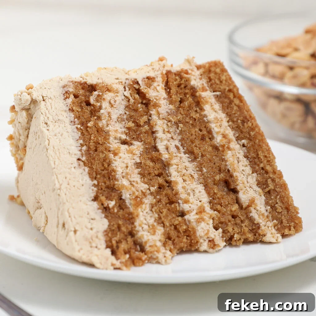44 Gluten-Free Dairy-Free Cake Recipes for Every Occasion 25 A slice of layered Peanut Butter Cake with light brown frosting sits on a white plate. A glass bowl with crunchy cereal is blurred in the background.