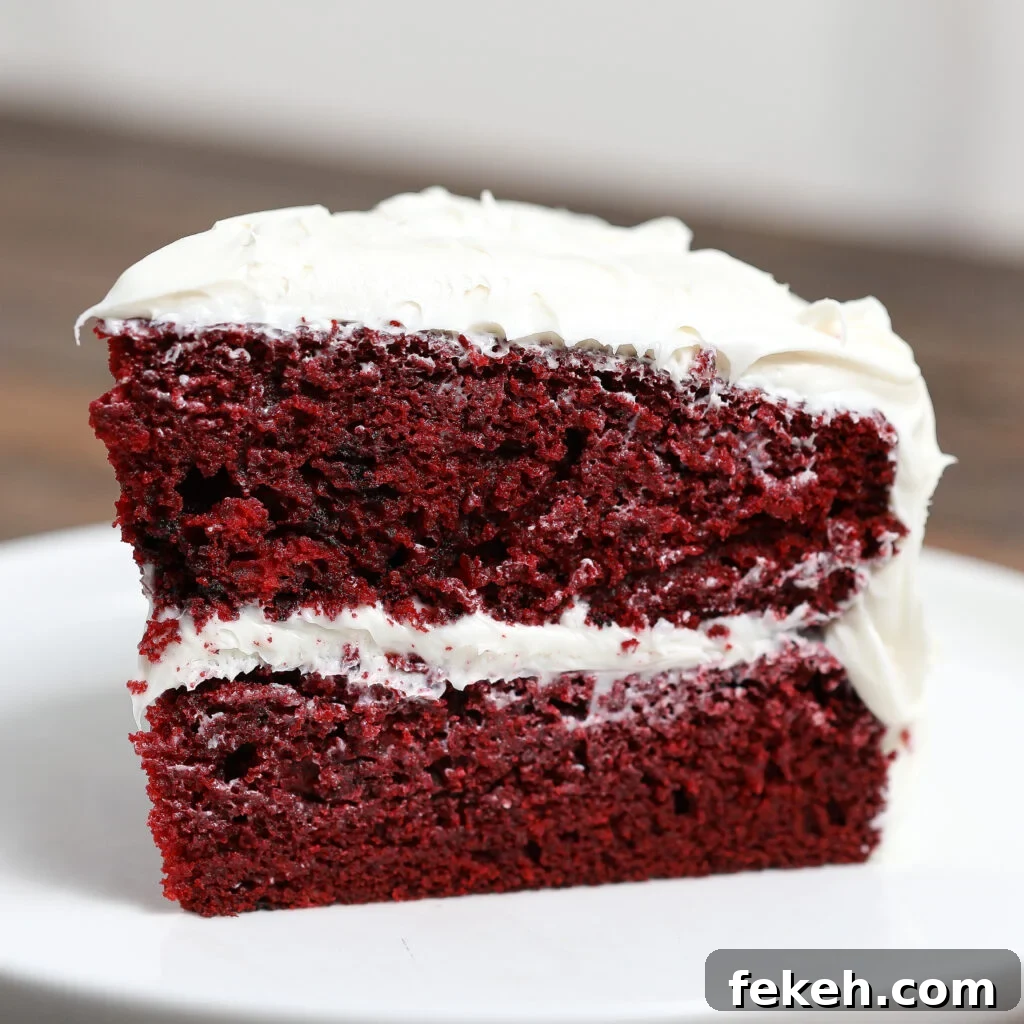 44 Gluten-Free Dairy-Free Cake Recipes for Every Occasion 43 A slice of Gluten Free Red Velvet Cake with Dairy Free Frosting, boasting two layers separated and topped with creamy white frosting, sits on a white plate against a blurred background.