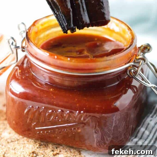 Smoked Pork Butt (Smoked Pork Shoulder) Recipe for Tender, Juicy Meat 24 Kansas City-style BBQ sauce in a mason jar sitting on gray and white napkin with some loose seasoning on the table in front