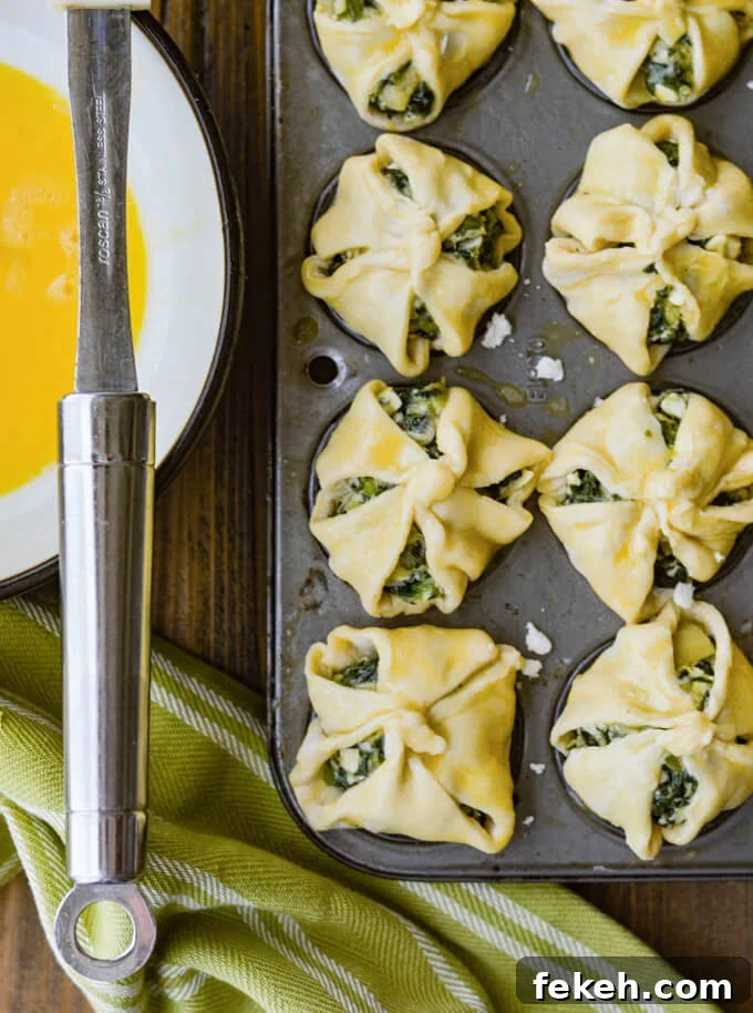 Spinach Puff Pastry Bites: Flaky Savory Appetizer Recipe 5 Unbaked puff pastry with spinach filling in mini muffin tins with egg wash on them