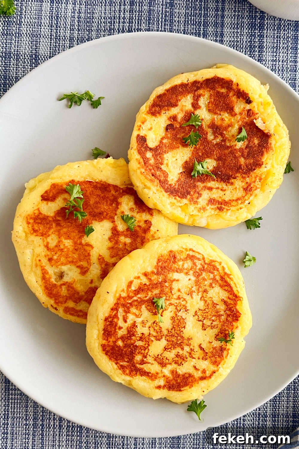 Crispy Mashed Potato Cakes (Potato Patties) Recipe 2 leftover mashed potato patties on a blue plate with parsley