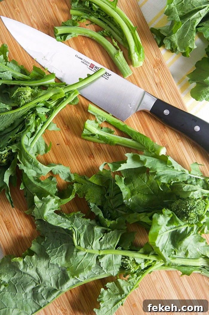 Garlicky Sautéed Broccoli Rabe with Lemon and Chili Flakes 4 Broccoli rabe being cut on a bamboo cutting board.