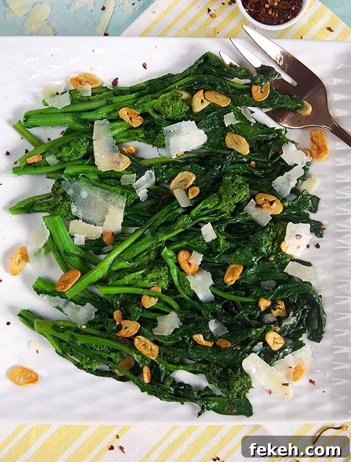Garlicky Sautéed Broccoli Rabe with Lemon and Chili Flakes 6 Broccoli rabe on a white square platter with crushed red pepper flakes in a bowl.