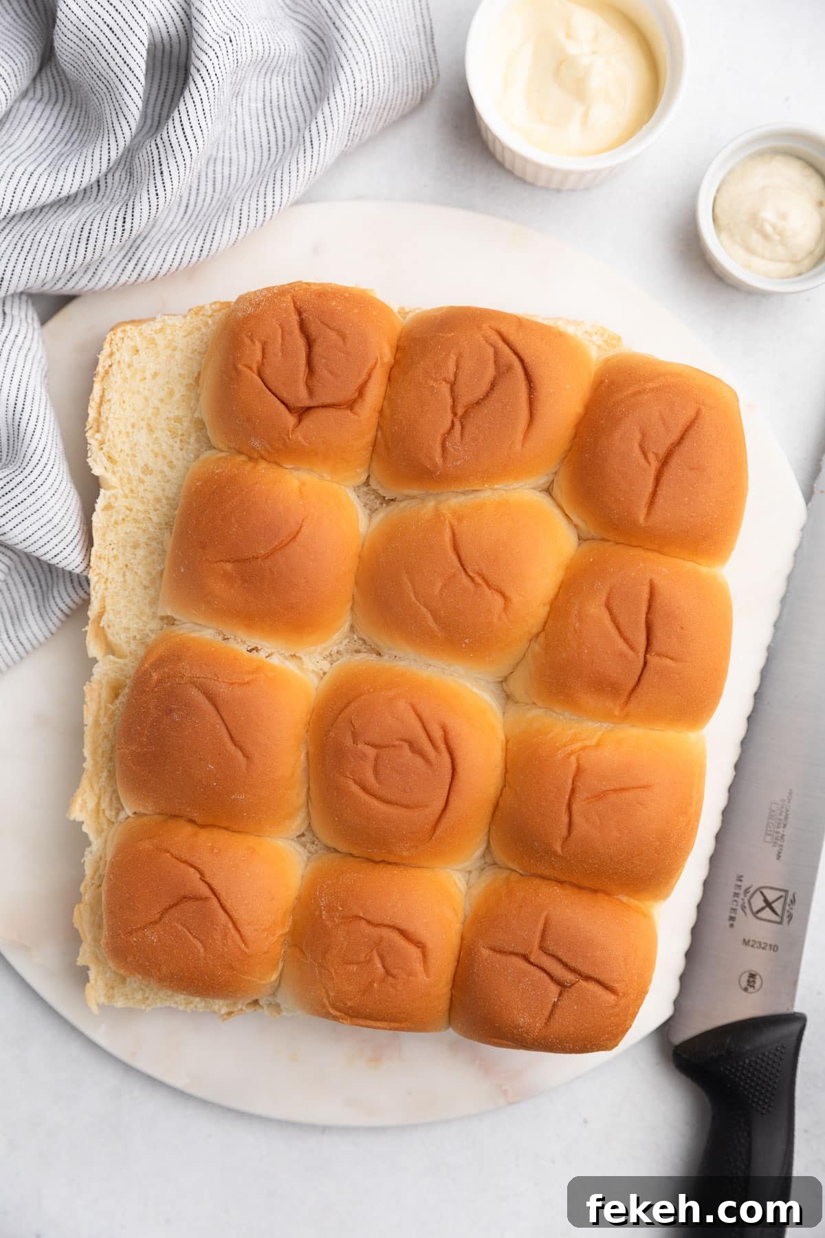 a slab of slider rolls sliced in half on a white marble board