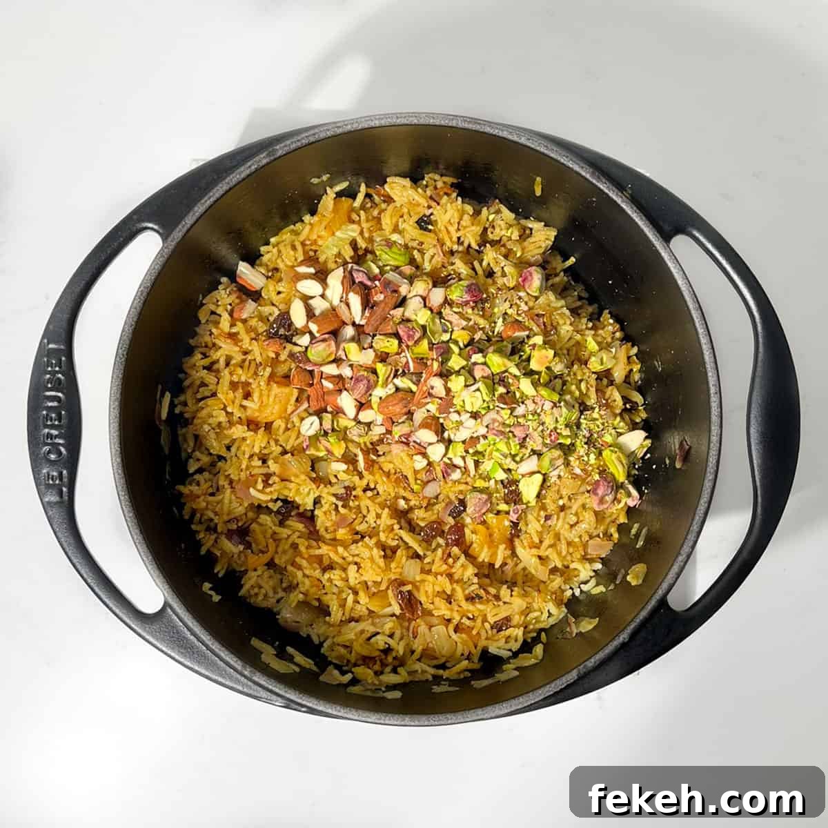 Majestic Moroccan Rice Pilaf with Saffron and Aromatic Spices 9 Adding nuts to cooked rice in a black cast iron saucepan.