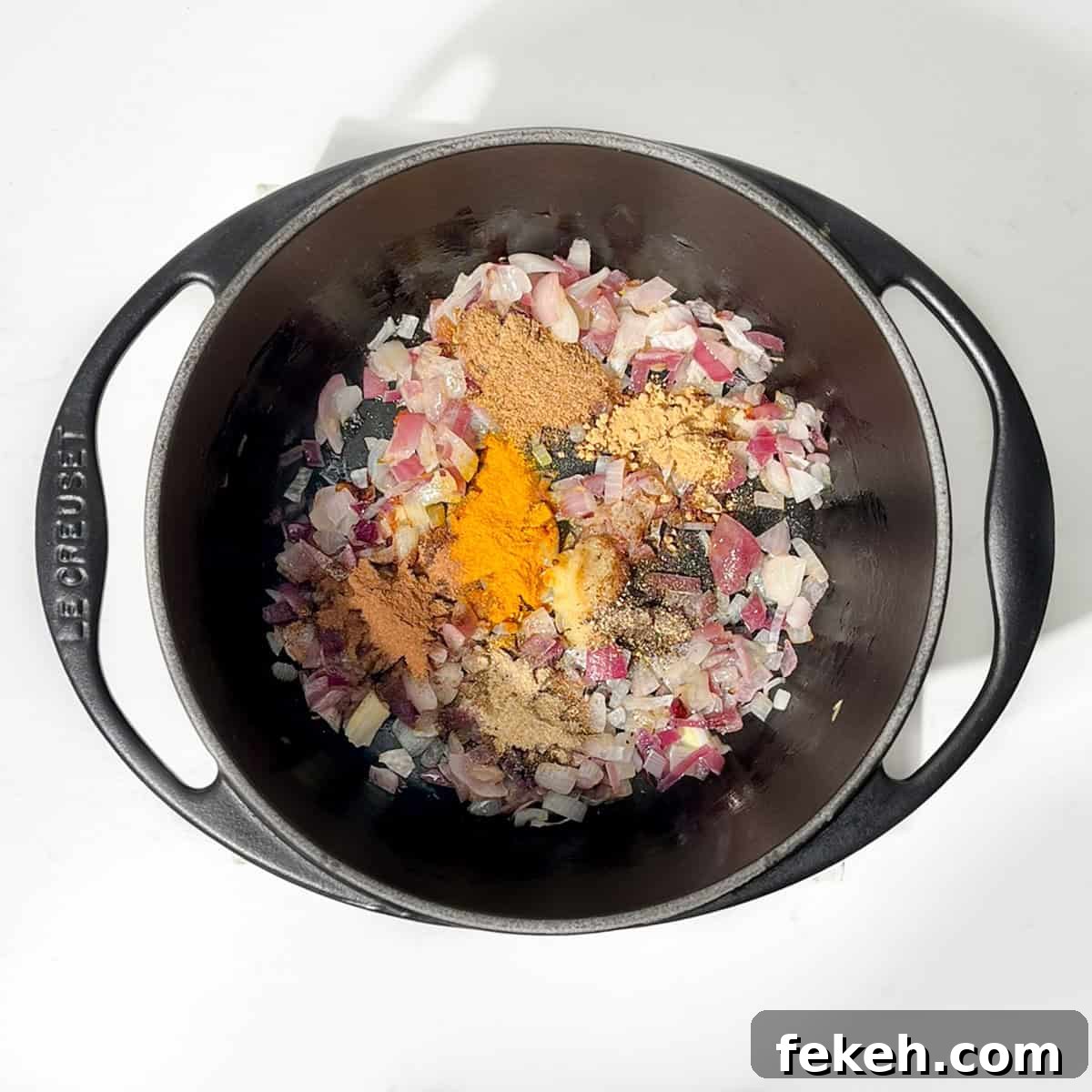 Majestic Moroccan Rice Pilaf with Saffron and Aromatic Spices 6 Adding spices to onions in a black cast iron saucepan.