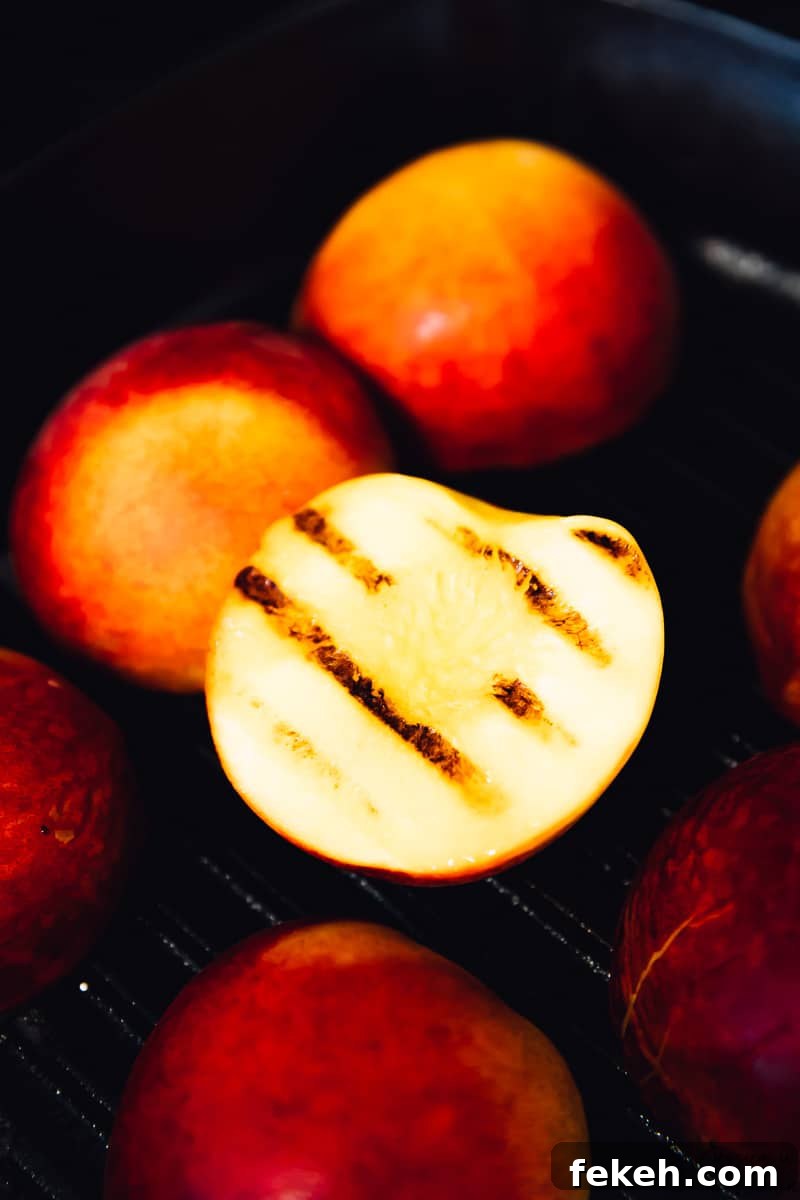 Close up of peaches grilling, with one flipped over to reveal the grill marks.