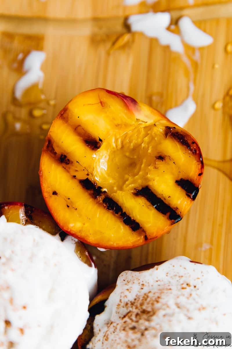 Overhead shot of grilled peaches, some topped with ice cream. 