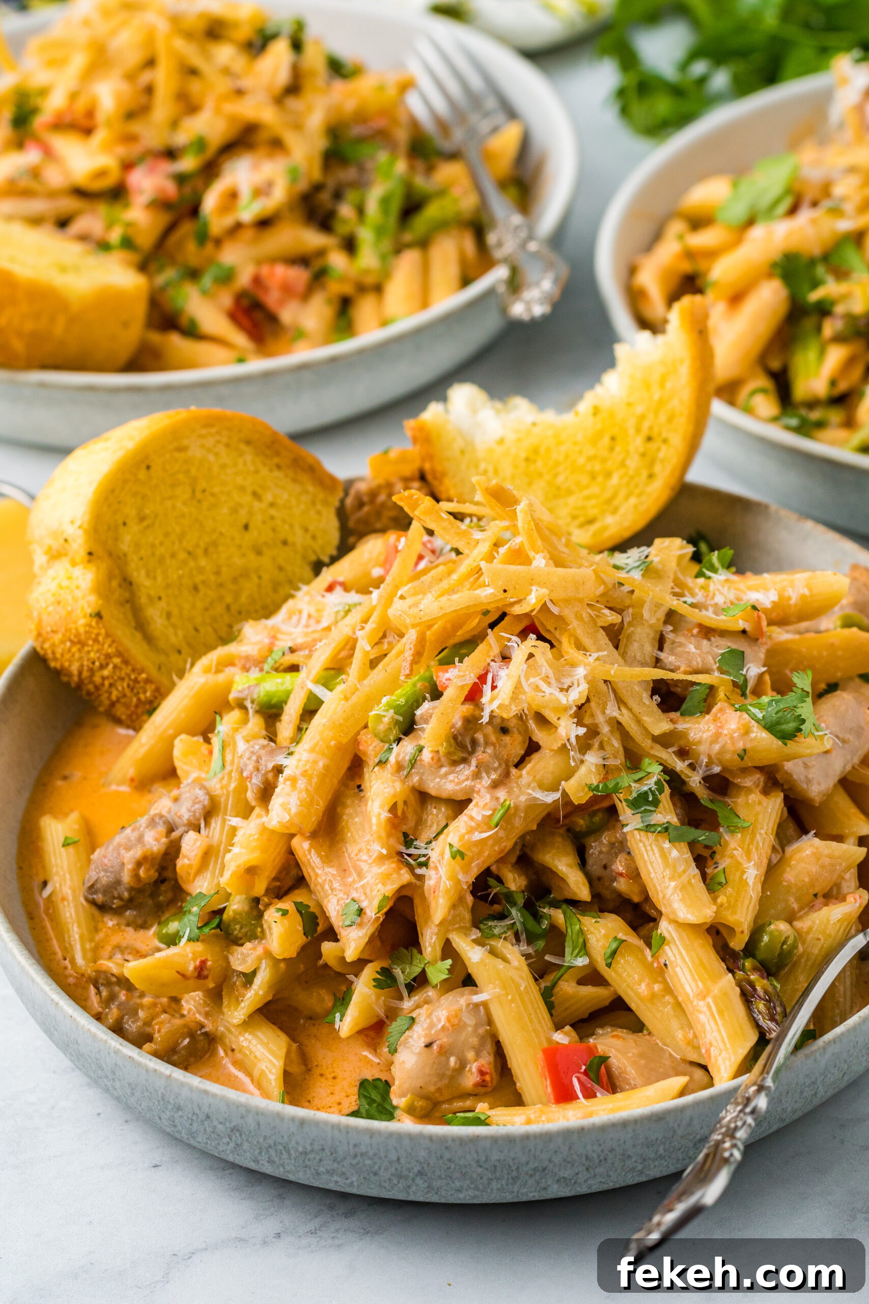 Cajun Chicken Pasta Recipe with Creamy Parmesan Sauce 2 Side view of Cajun Chicken Pasta served in a dish with garlic bread.