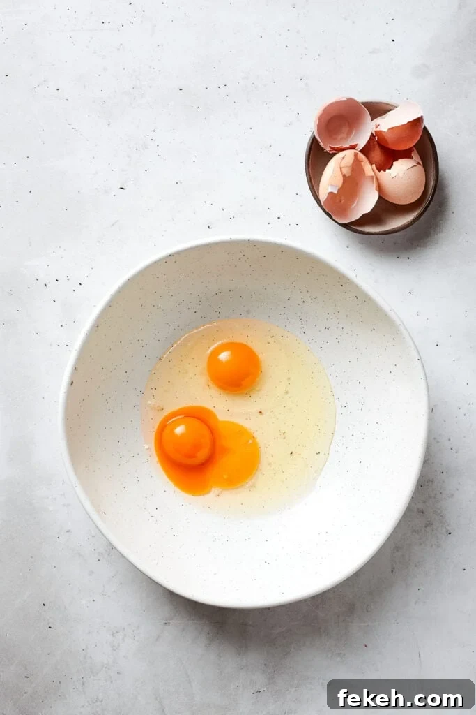 Blonde Brownies | Vanilla Blondies with White Chocolate and Pecans! Two eggs and an egg yolk in a white bowl.