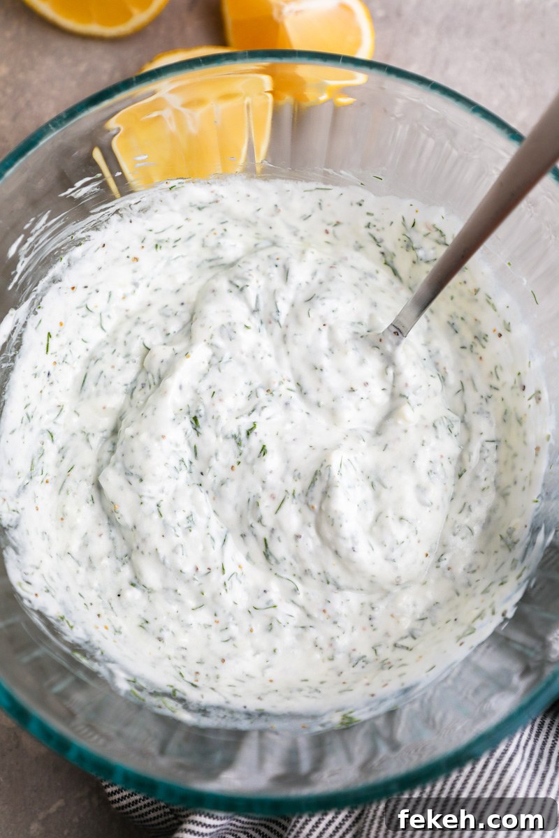 Creamy Cucumber Salad with Tangy Greek Yogurt Dressing 4 A clear glass bowl filled with a tzatziki-style dressing for a cucumber salad