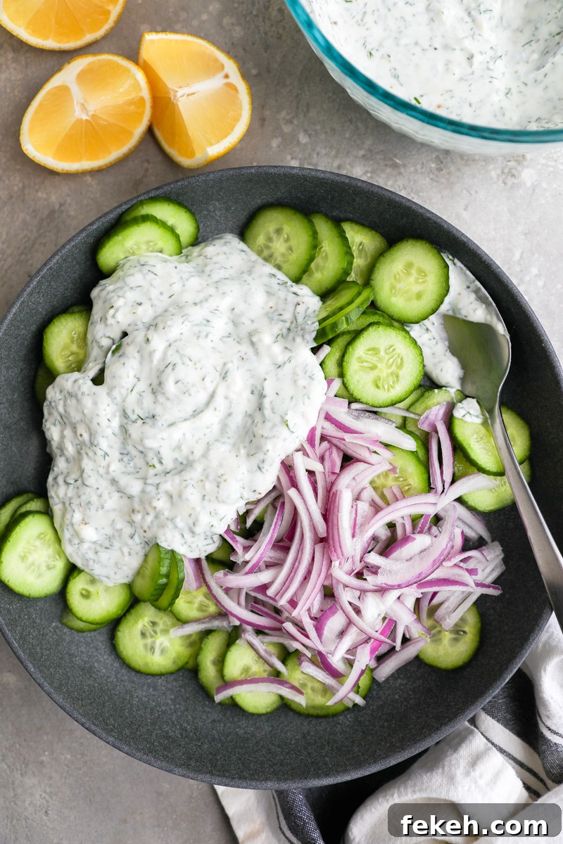 Creamy Cucumber Salad with Tangy Greek Yogurt Dressing 5 A large serving bowl filled with thinly sliced cucumbers, red onion and a creamy tzatziki-style dressing