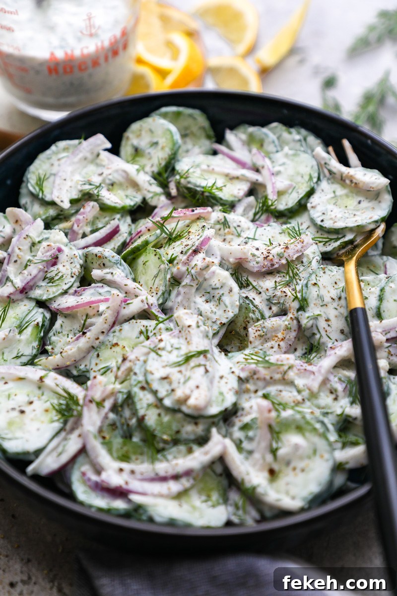 Creamy Cucumber Salad with Tangy Greek Yogurt Dressing 6 A bowl of creamy cucumber salad surrounded by fresh lemon wedges and a jar of zesty Greek yogurt dressing