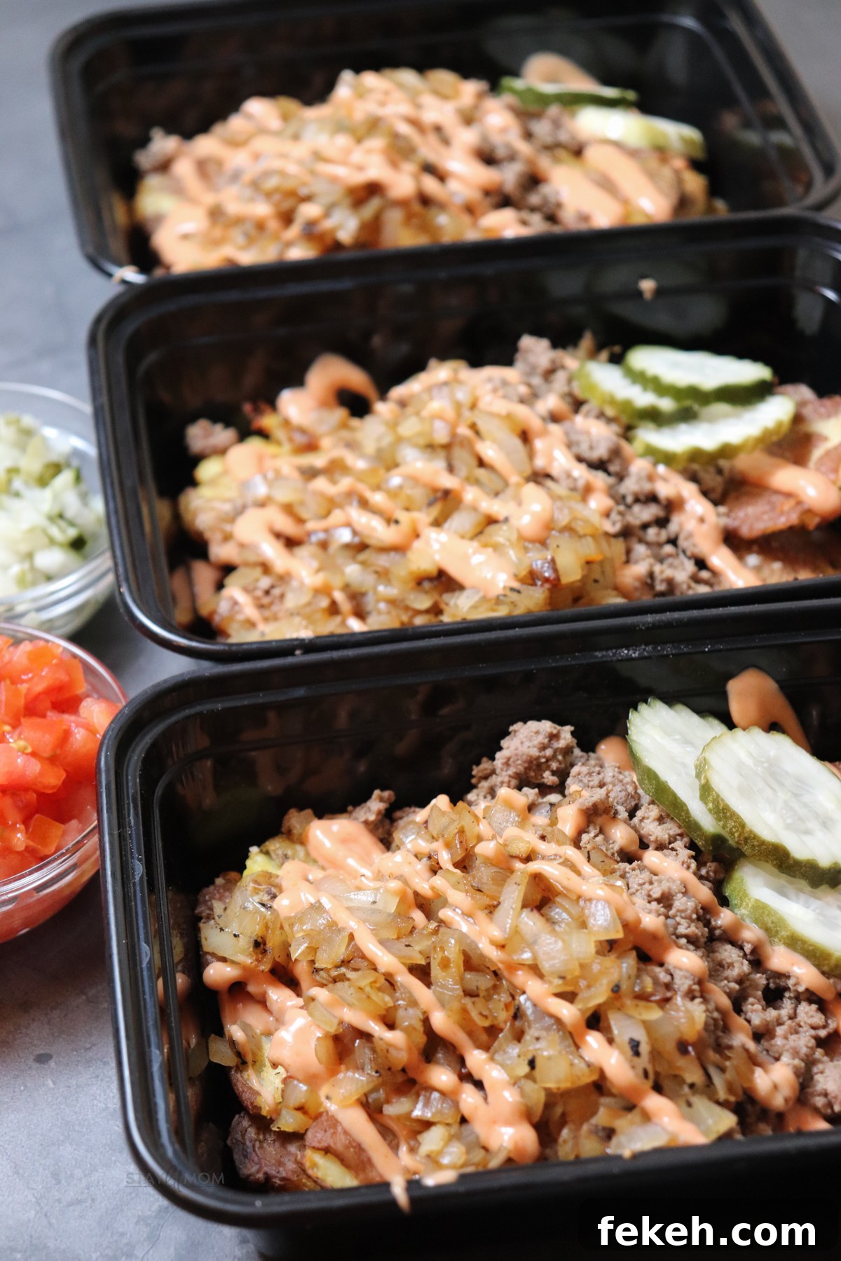 Animal-Style Burger Bowls: Low-Carb Cheeseburger Skillet Bowl 5 3 meal prep containers lined up and filled with crispy potatoes, ground beef, caramelized onions, and topped with pickles and sauce.