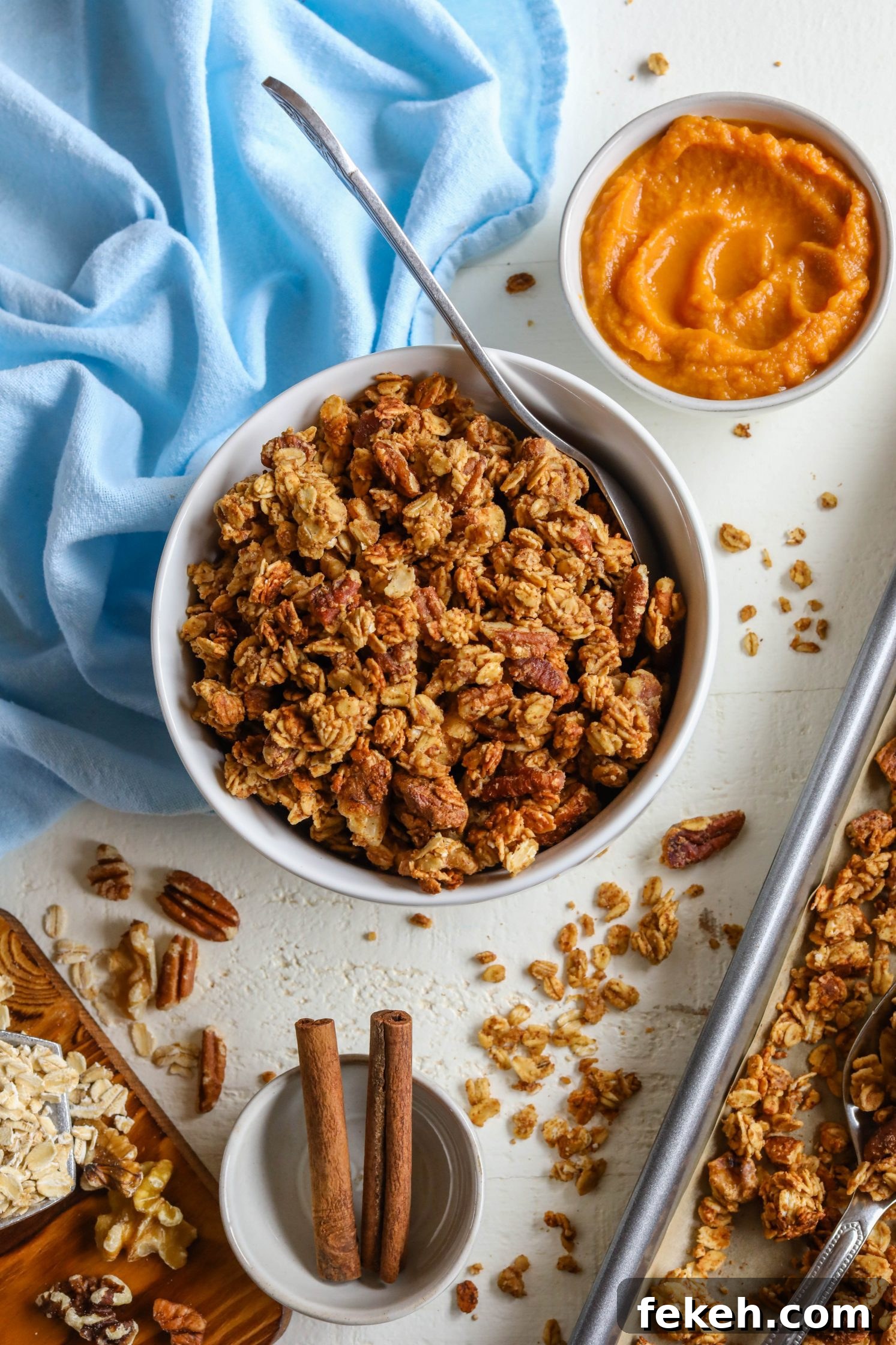 Sweet Potato Spice Granola Recipe for Cozy Fall Mornings 2 Sweet Potato Spice Granola served in bowl with a spoon and sweet potato puree on the side with blue towel and cinnamon