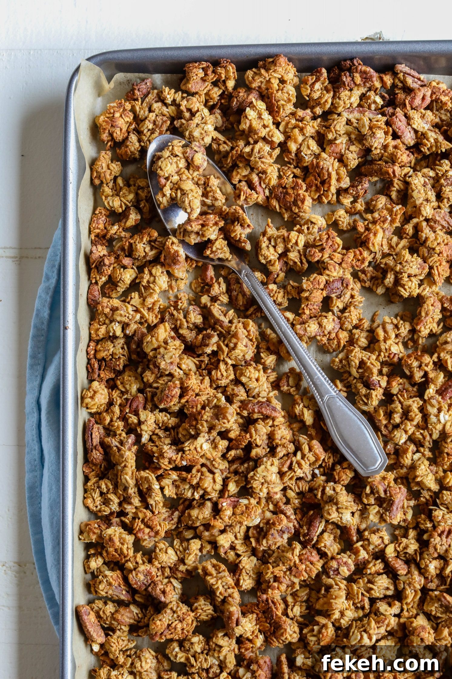 Sweet Potato Spice Granola Recipe for Cozy Fall Mornings 7 Sweet Potato Spice Granola baked on parchment lined baking sheet with spoon