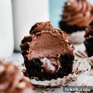 Nutella Chocolate Cupcakes with Cream Cheese Nutella Frosting 11 A nutella cupcake with a bite missing and gooey nutella showing in the center.