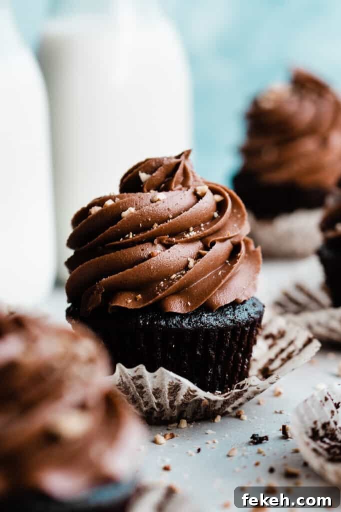 Nutella Chocolate Cupcakes with Cream Cheese Nutella Frosting 3 A close-up of a nutella cupcake topped with a generous swirl of nutella frosting with milk bottles in the background.