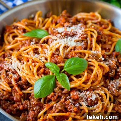 Authentic Italian Bolognese Pasta Recipe: Rich Meat Sauce Guide 2 A pan of pasta bolognese garnished with basil sprigs and parmesan cheese.