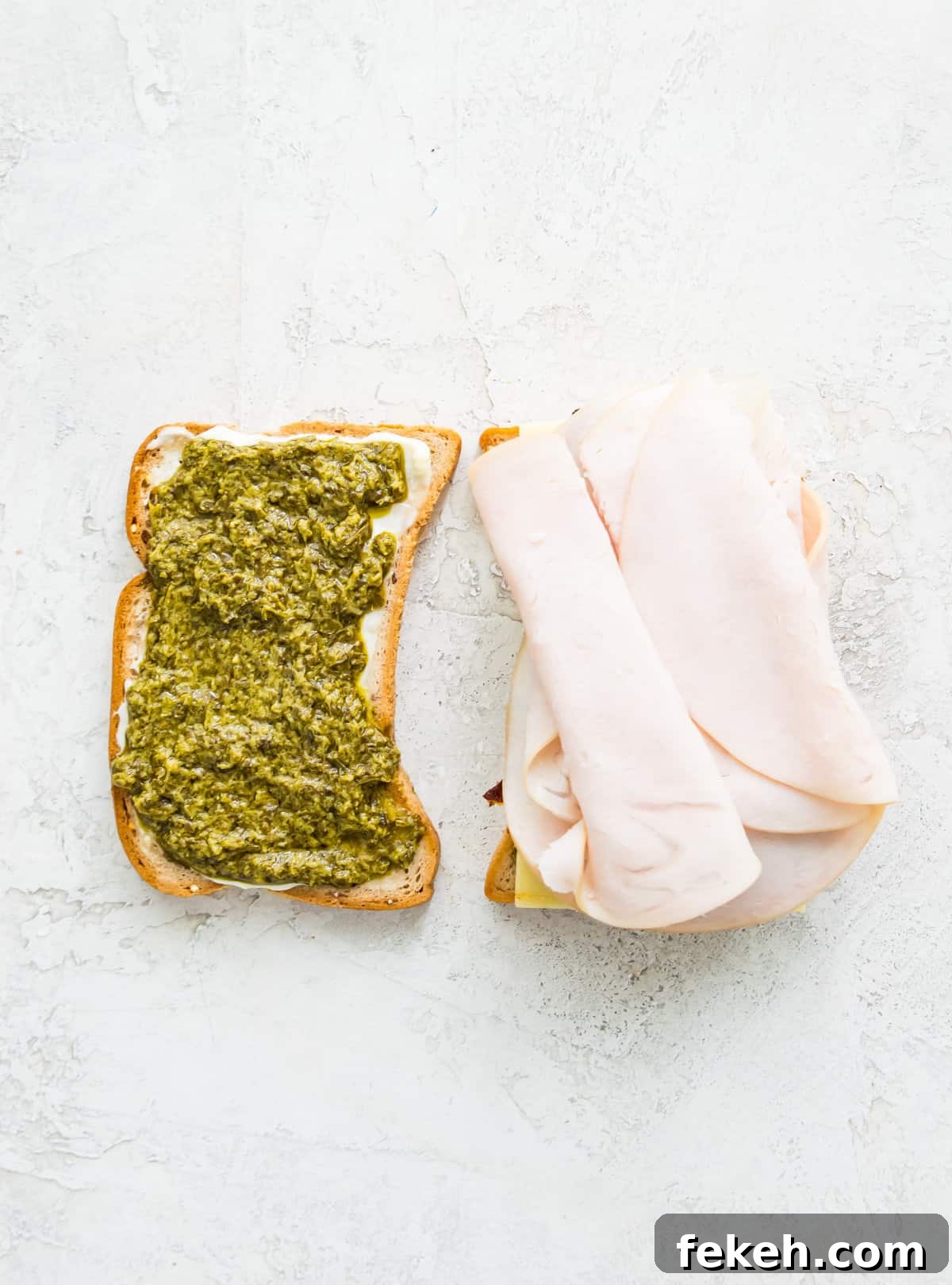 Grilled Turkey and Pesto Sandwich Recipe 5 Two pieces of bread, one with pesto on it and one with turkey meat on it.