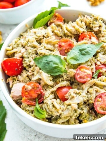 A bowl of tuna pasta pesto topped with fresh basil.