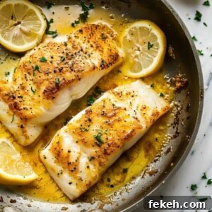 Pan fried cod with lemon butter sauce in a pan.