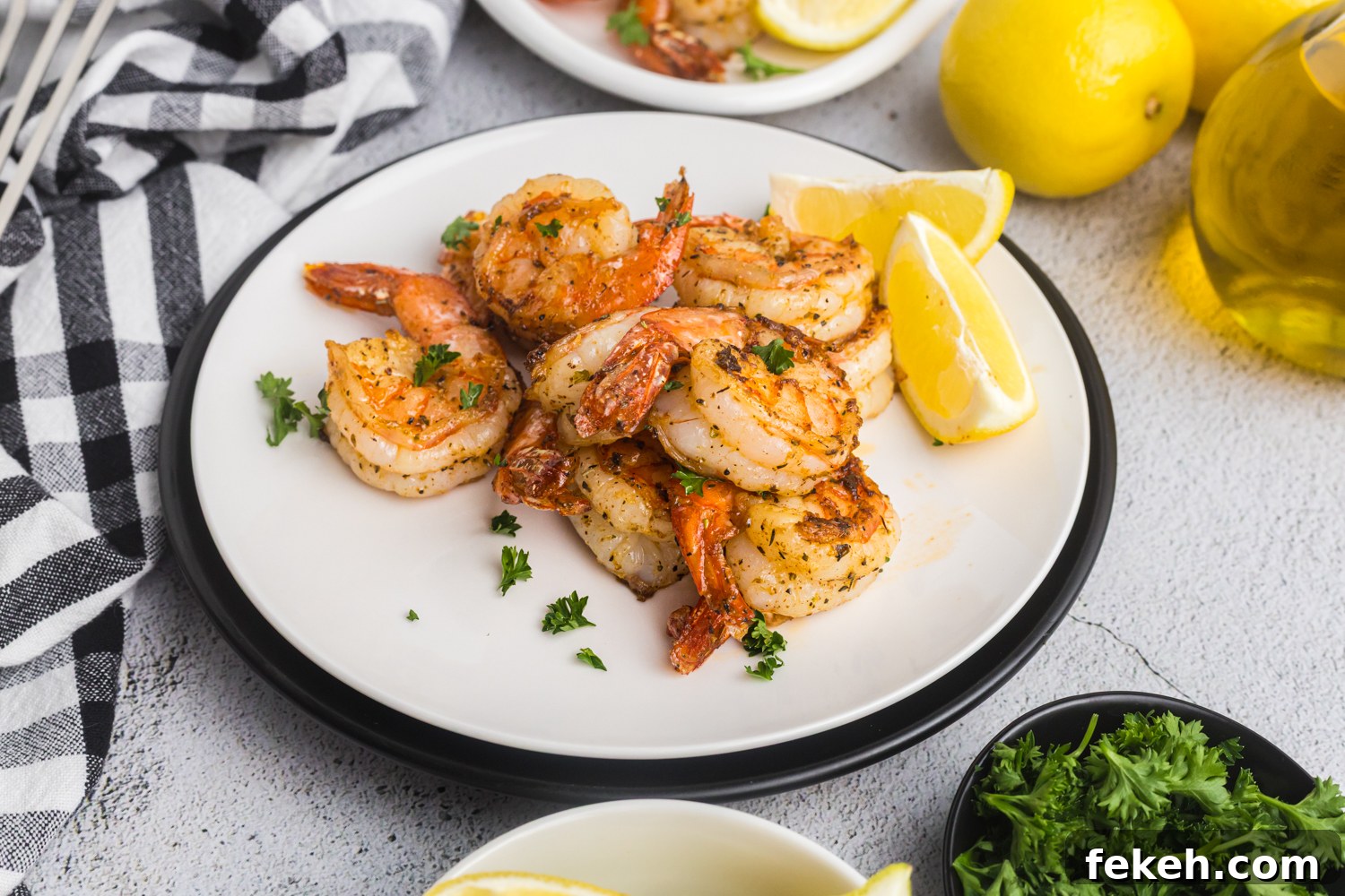 Cooked shrimp served on a white plate with lemon wedges and parsley, ready to eat.