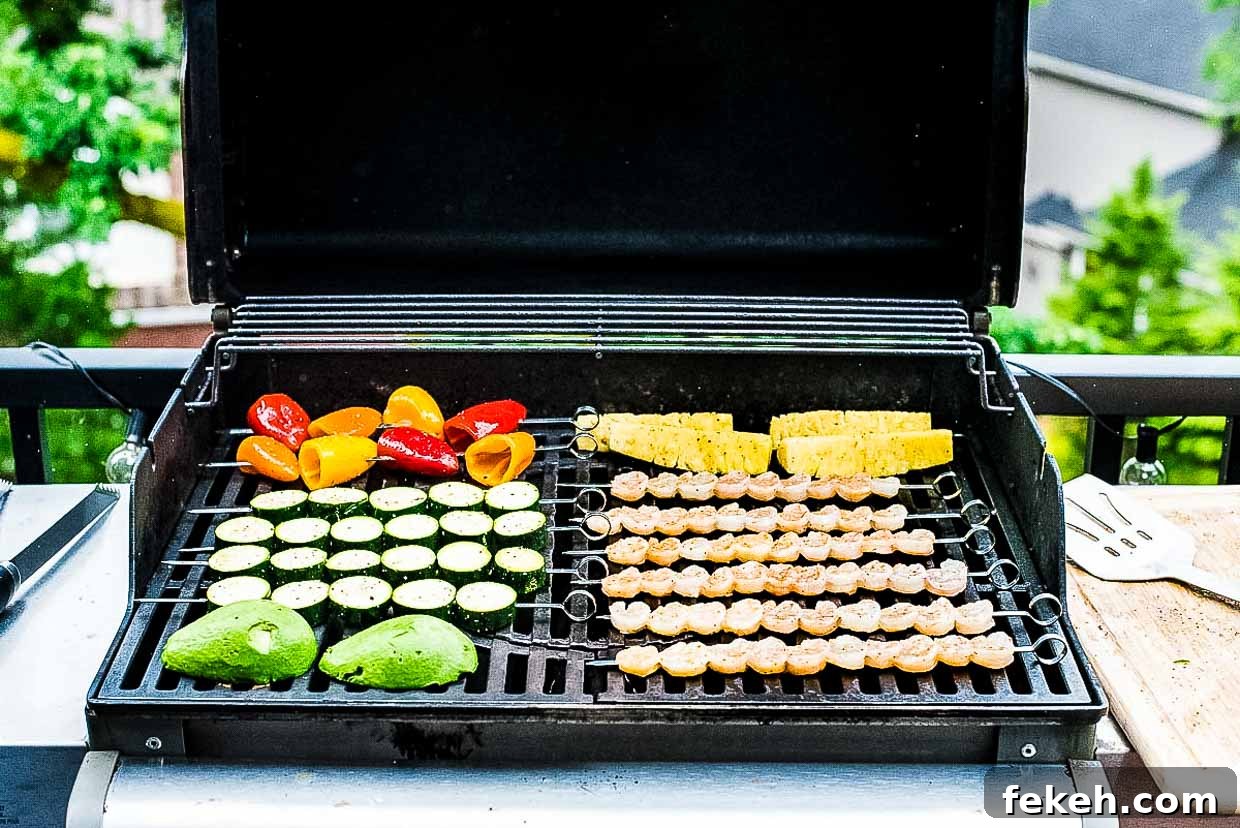 Skewers of shrimp, pineapple, peppers, zucchini and avocado on the grill. 