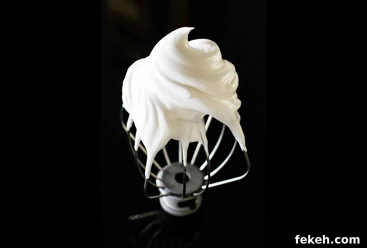 Whipped meringue on an upside down wire whisk from a stand mixer.