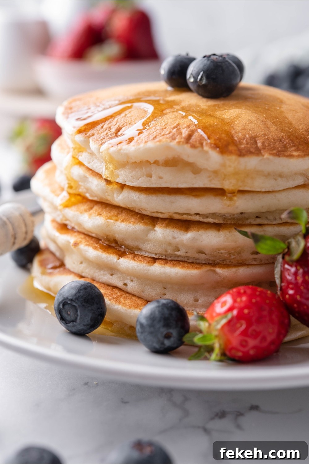 Light and Fluffy Vegan Pancakes Without Eggs 3 Close up of a stack of pancakes covered in maple syrup with berries on top of the pancakes and surrounding them on the plate.
