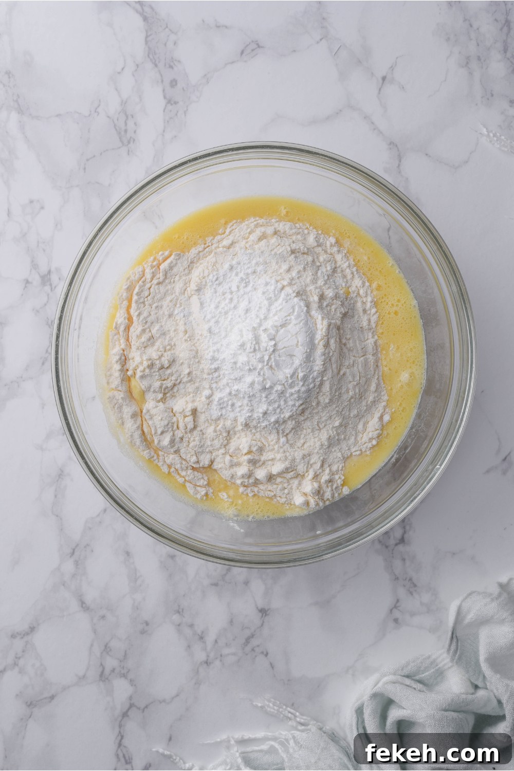 Light and Fluffy Vegan Pancakes Without Eggs 6 A clear bowl with a combination of wet and dry ingredients that have not been mixed together.