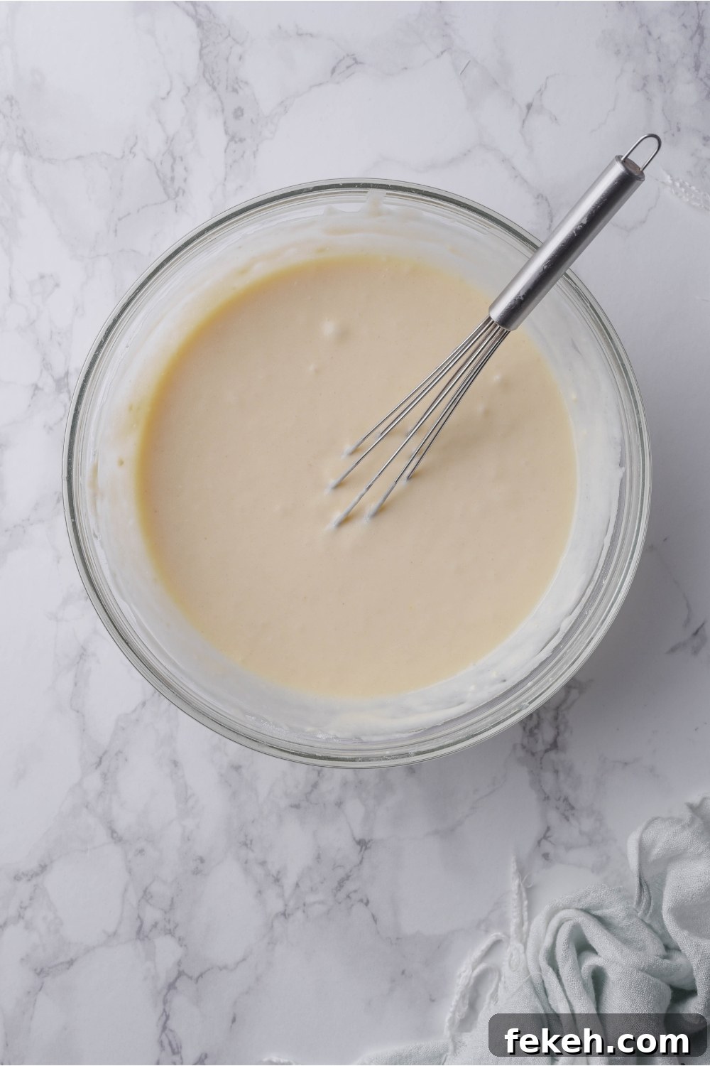 Light and Fluffy Vegan Pancakes Without Eggs 7 A clear bowl with pancake batter and a whisk in it.