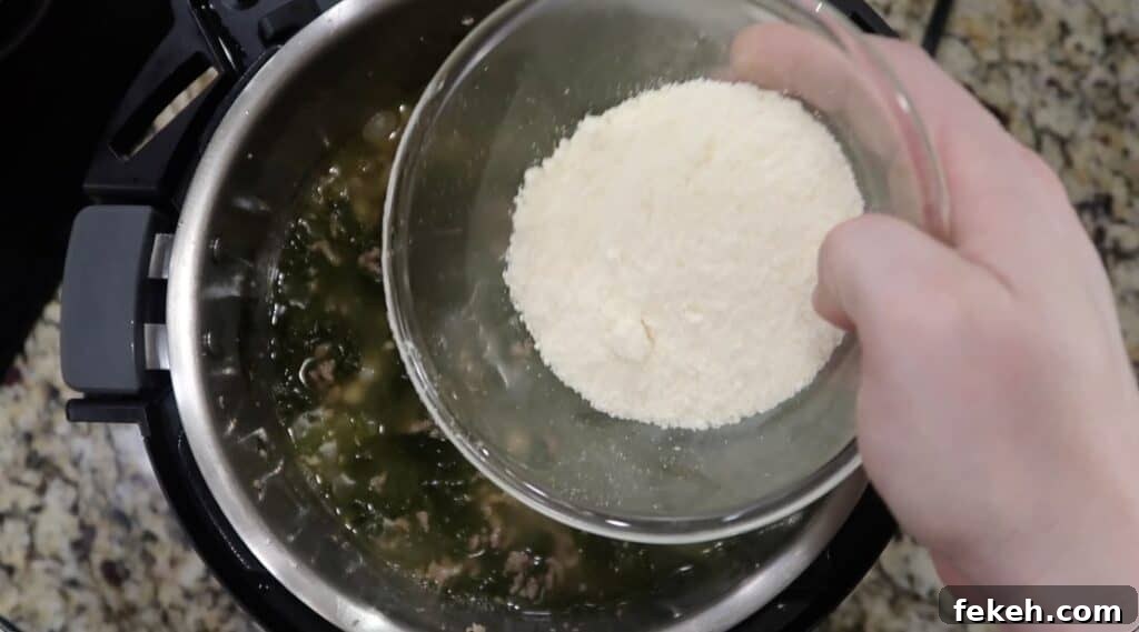 Instant Pot Escarole and White Bean Soup Recipe 20 Adding Parmesan to pot.