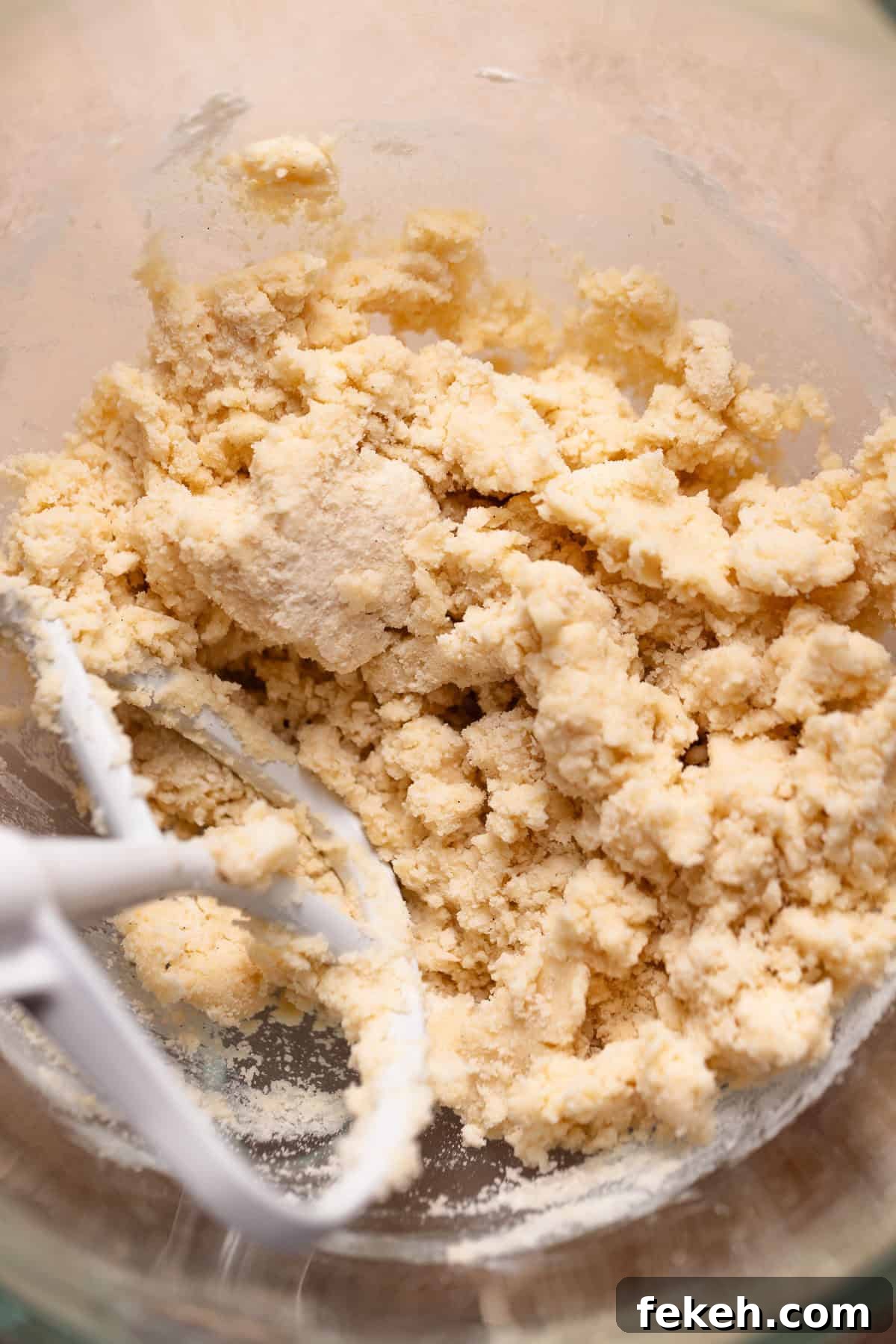 Shortbread dough in a glass mixer bowl.