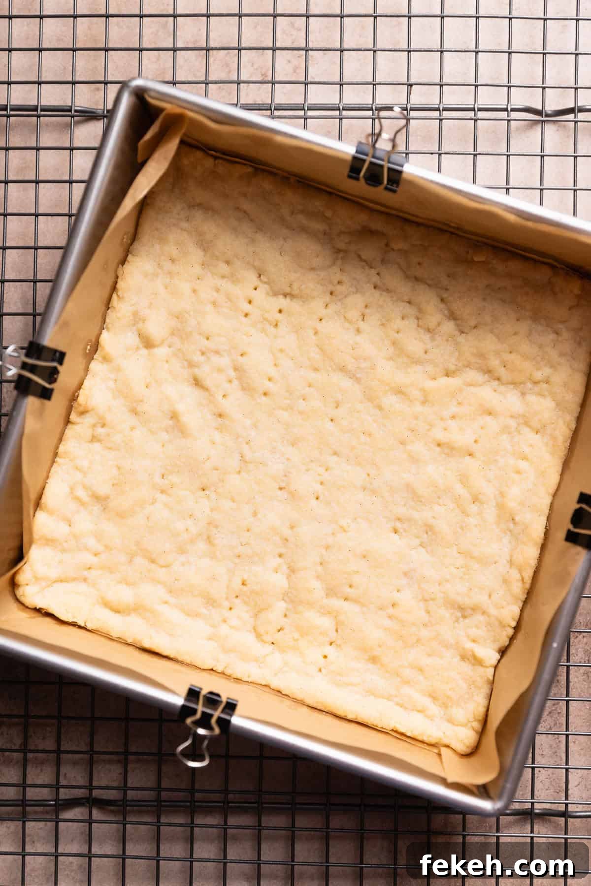A pan with the baked shortbread crust cooling on a wire rack.