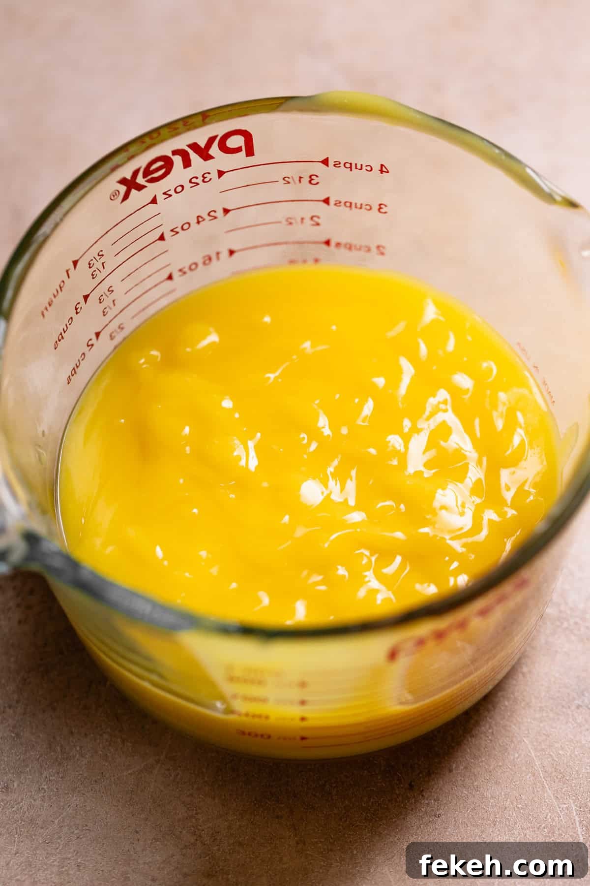 Lemon curd in a glass measuring cup.