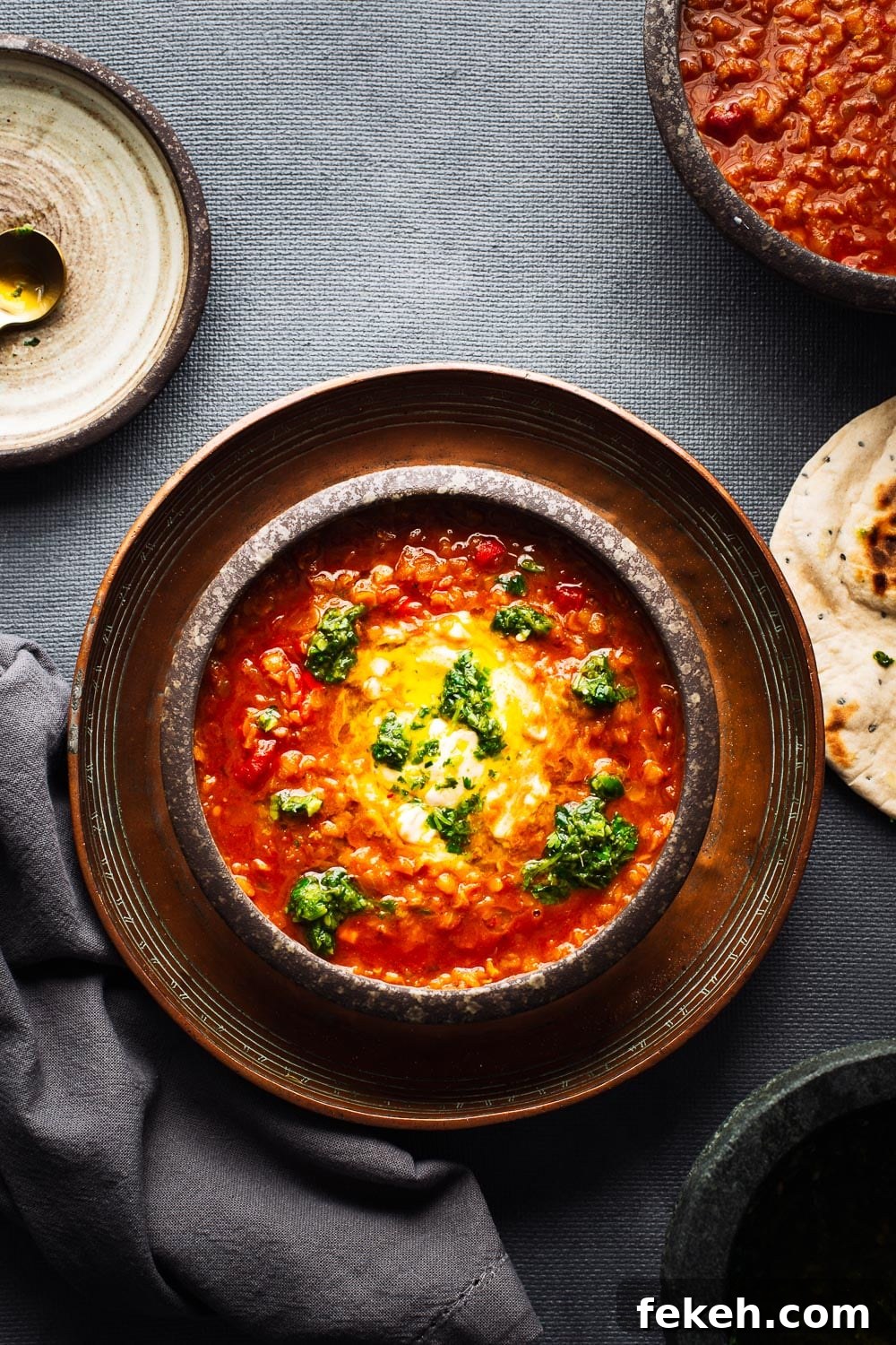 Spicy Harissa Lentil Soup with Fresh Cilantro Salsa 2 Bowls of bright red lentil soup viewed from above on a dark grey background.