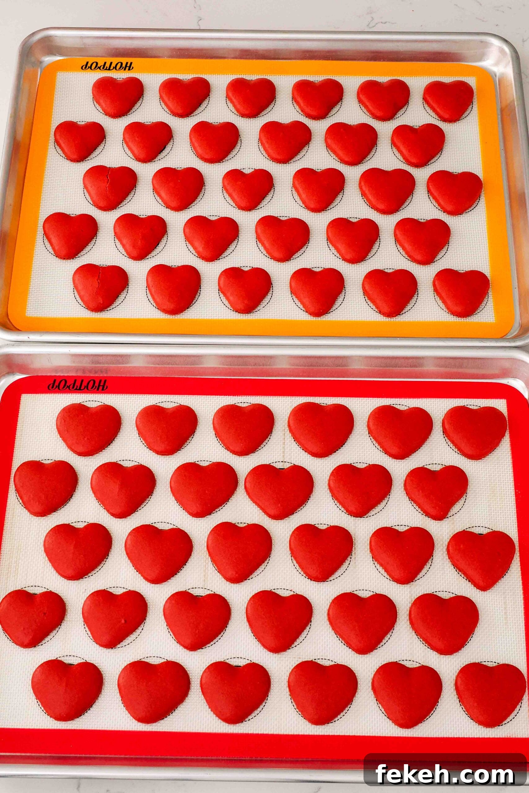 Freshly baked heart macarons on silicone macaron mats.