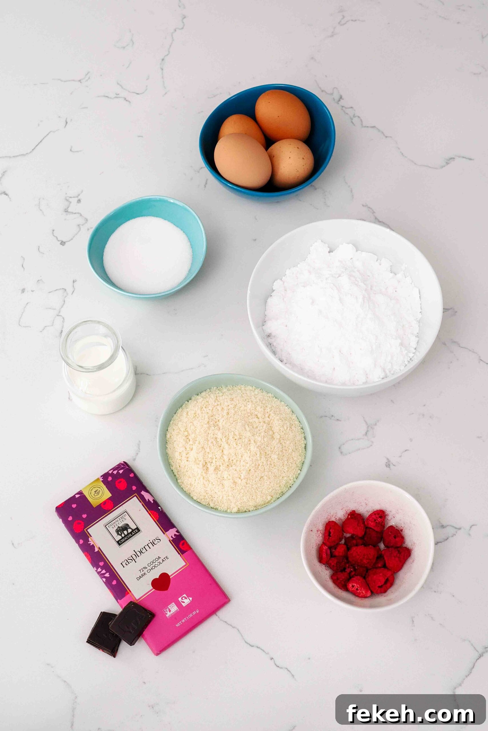 Ingredients for chocolate raspberry macarons on a quartz countertop.