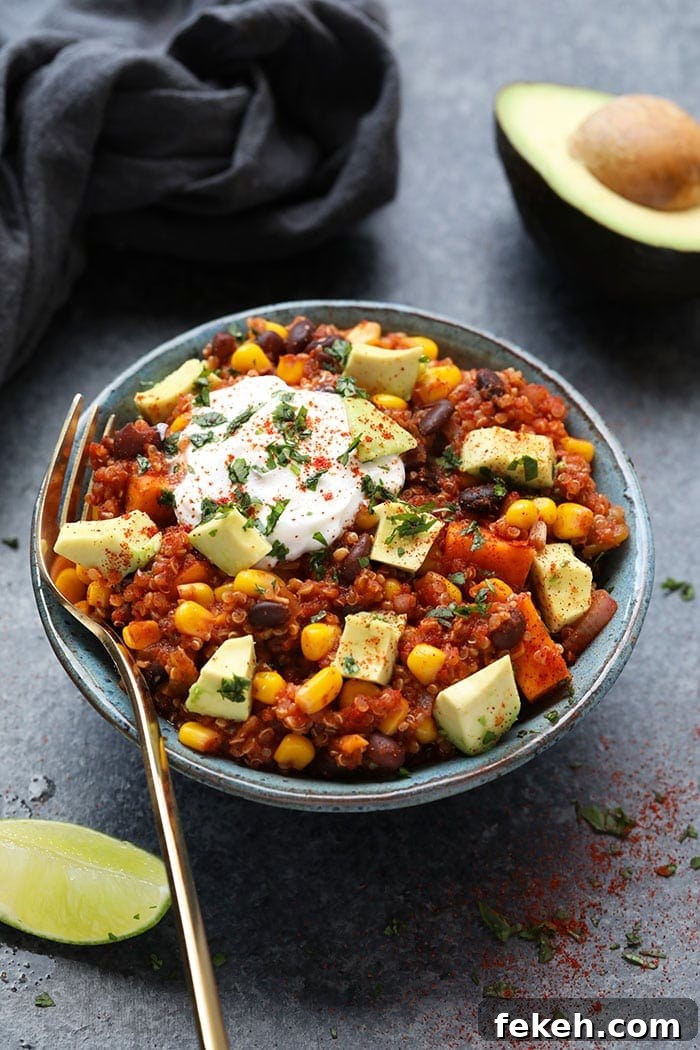 Incredible Mexican quinoa made in the slow cooker with tons of plant-based ingredients such as sweet potatoes and beans! Mexican quinoa in bowl with yogurt and sliced avocado