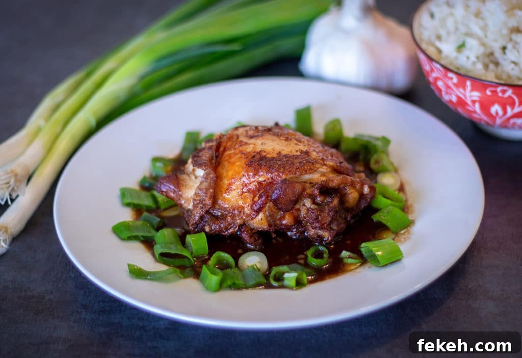 Instant Pot Crispy Chicken Adobo on a white plate with scallions, garlic and white rice