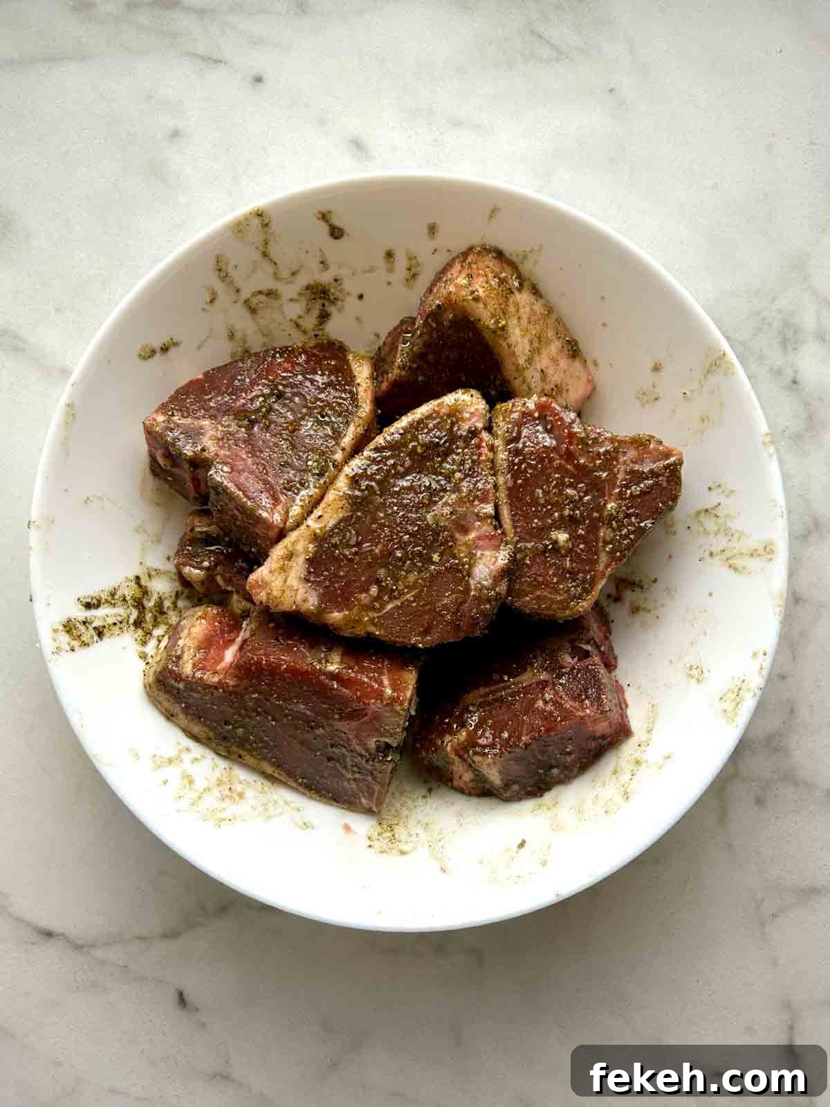 lamb loin chops mixed with oil and seasonings in bowl.