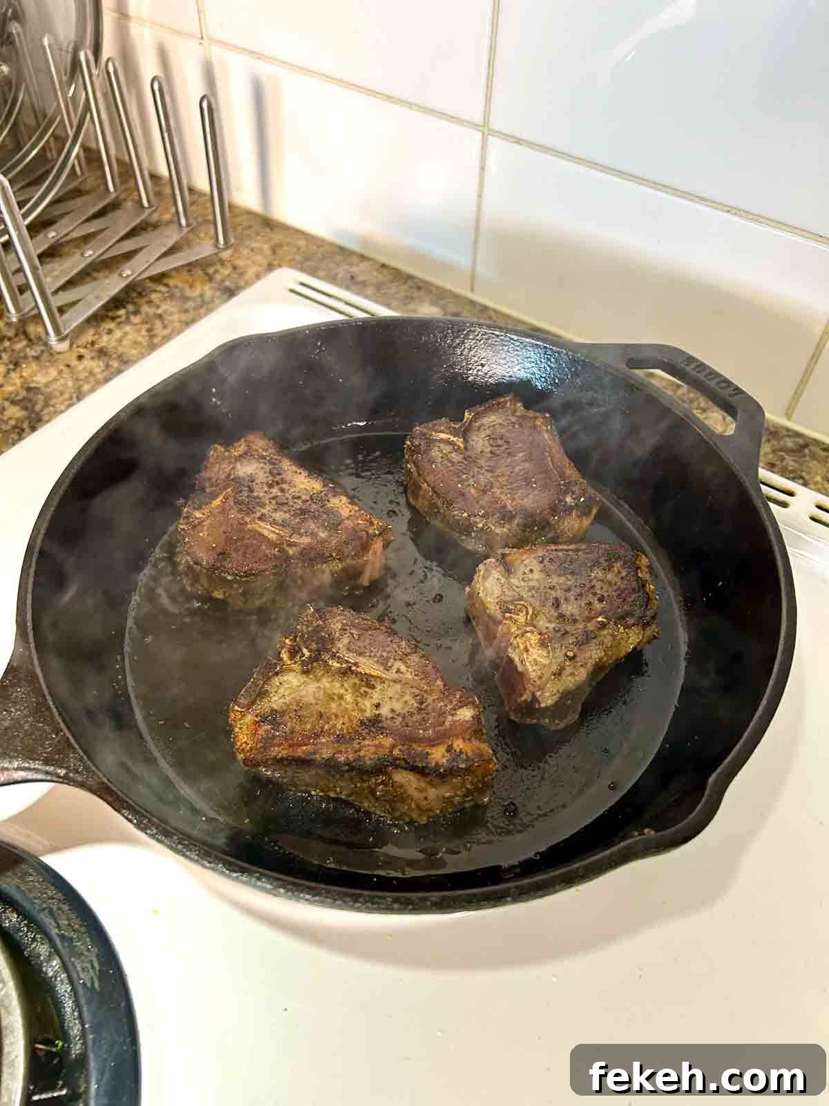 baked lamb loin chops being seared in cast-iron pan.