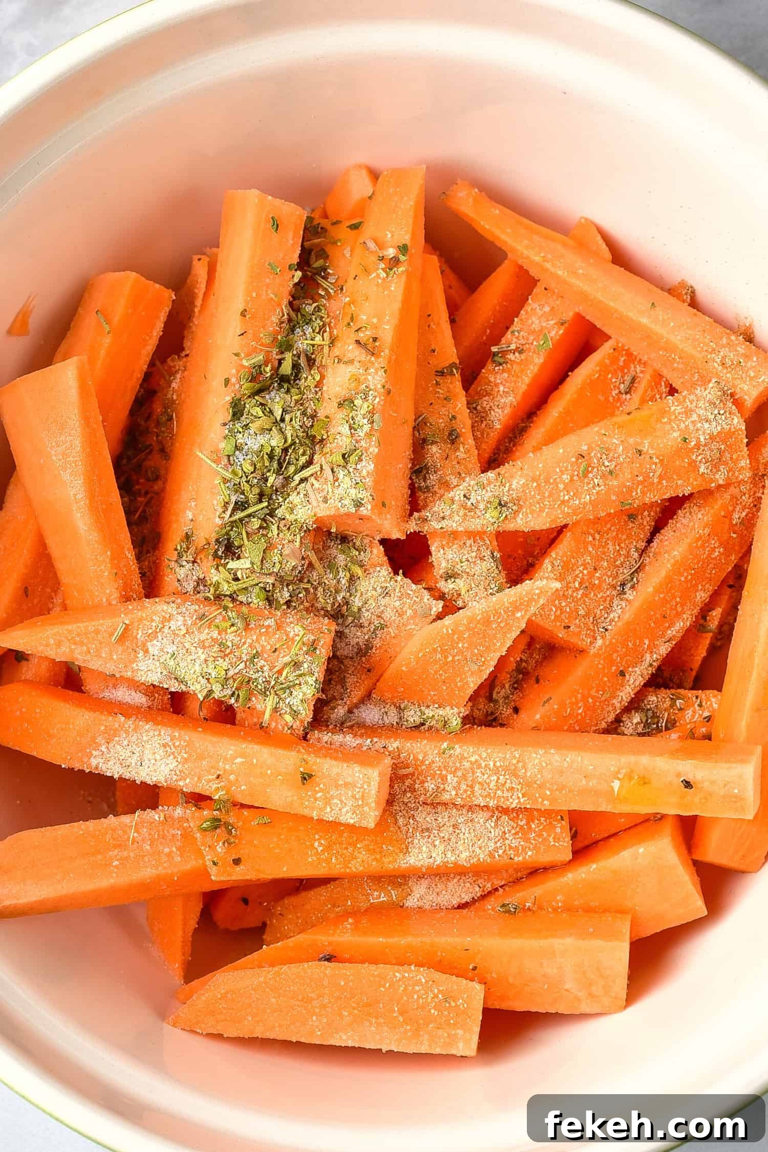 Spices sprinkled on top of sweet potato wedges.