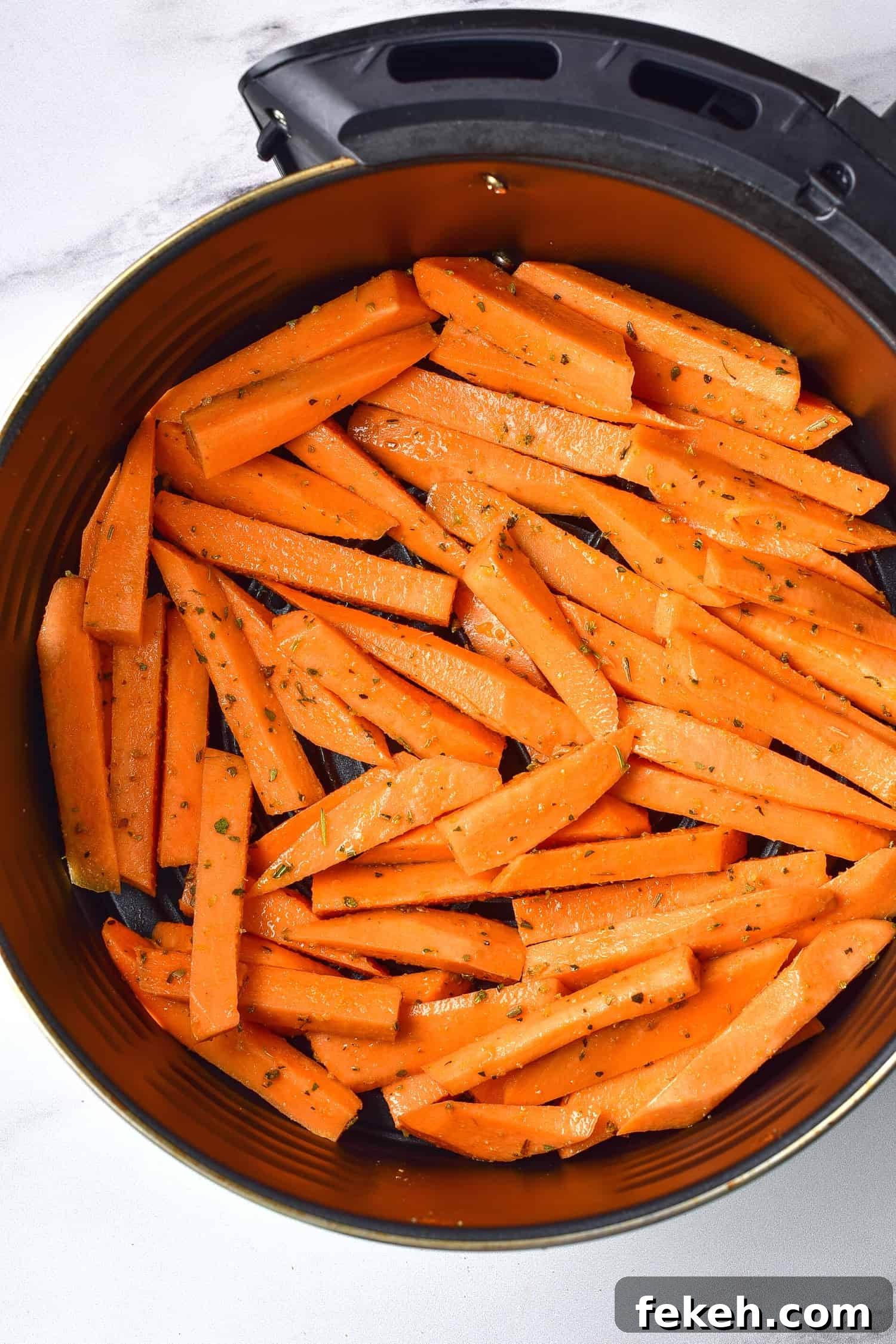Top down view of a layer of sweet potato fries in air fryer basket.