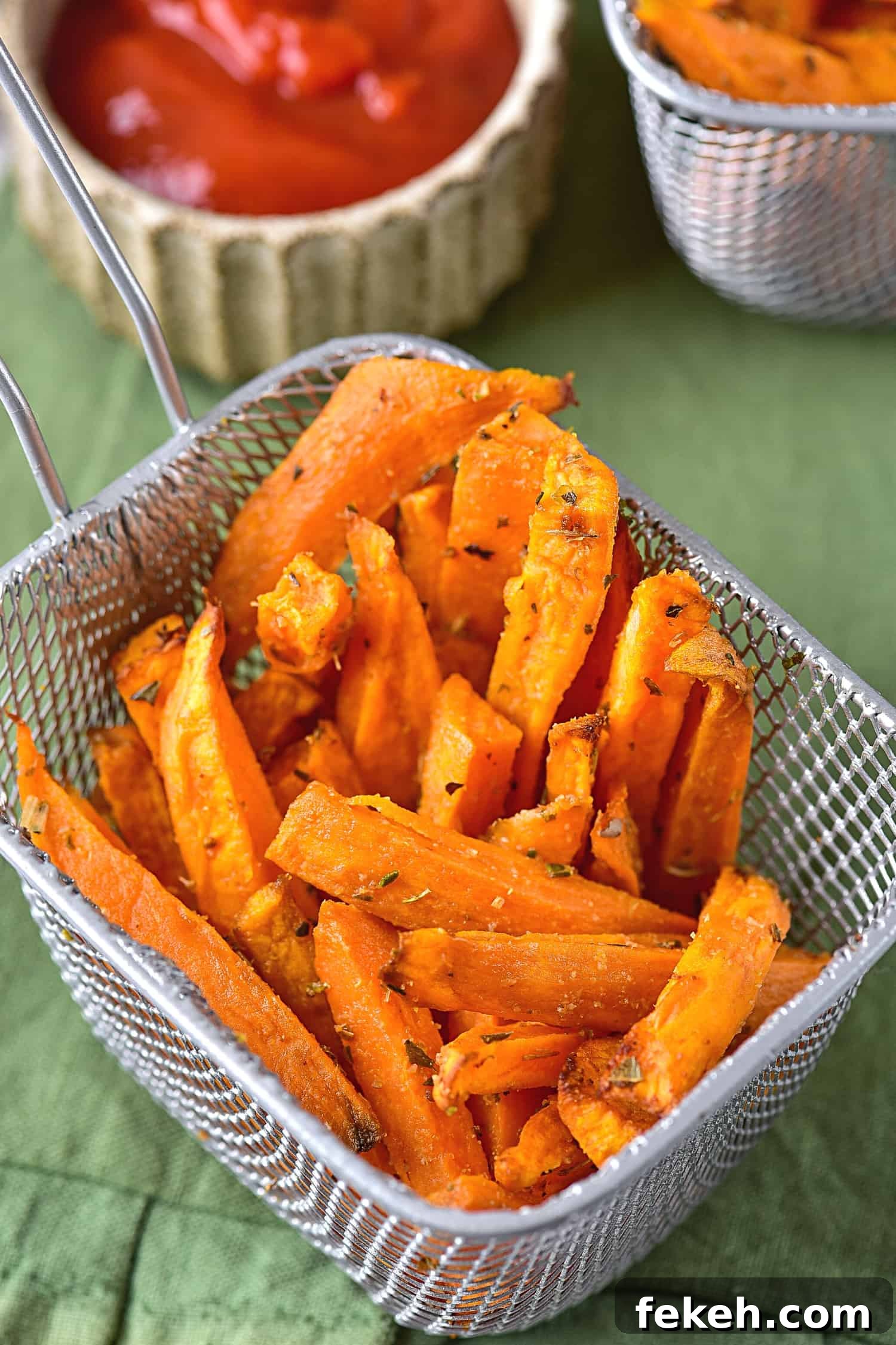 A basket of air fryer sweet potato fries on green cloth.