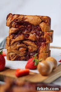 Peanut butter and jelly yogurt loaf cake on top of wooden cutting board in a standing position. cake has a strawberry jam swirl on top and is sliced to show texture.