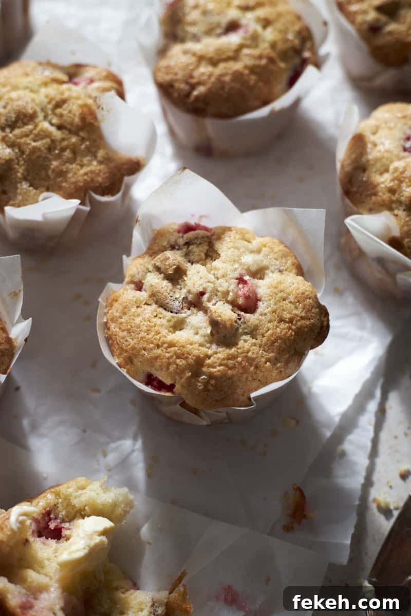 Strawberry Almond Muffins Recipe with Crispy Streusel Topping 2 Strawberry Almond Muffins on white parchment paper.